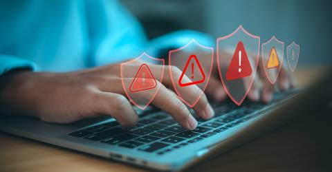 Man achter laptop krijgt alert meldingen met de icoontjes van rode driehoeken en uitroeptekens