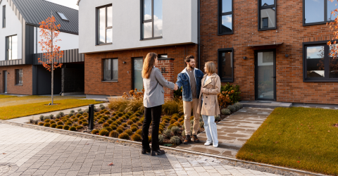 Makelaar schudt de hand van een gelukkig stel dat een huis koopt